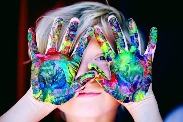 A child with a rainbow of colours painted on their hands