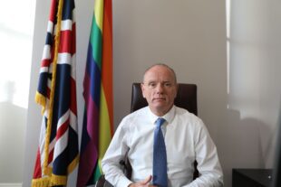 Landscape photo of Mike Freer in front of the Union Jack and LGBT flags